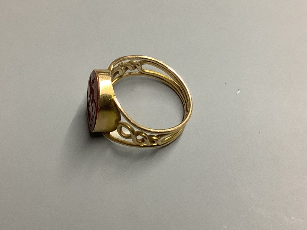 A yellow metal and carved oval Jasper set signet ring, with pierced shank, the matrix carved with two cherubs, size O gross 3.7 g.